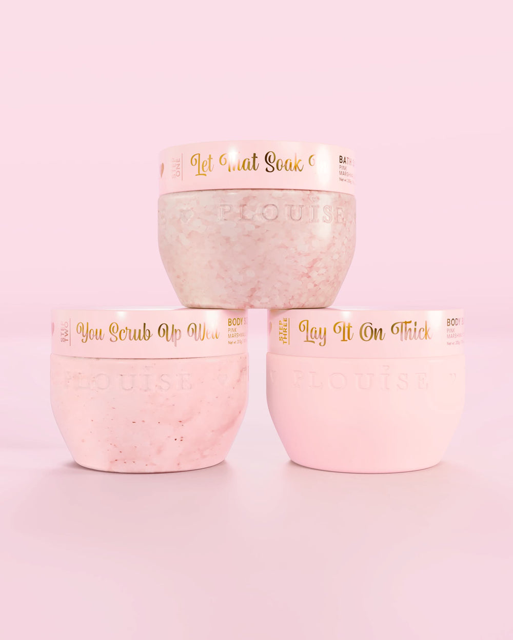 Tre P.Louise Hop Into Self-Care Pink Marshmallow rosa behållare med badsalt, kroppsskrubb och kroppssmör med guldtext på rosa bakgrund