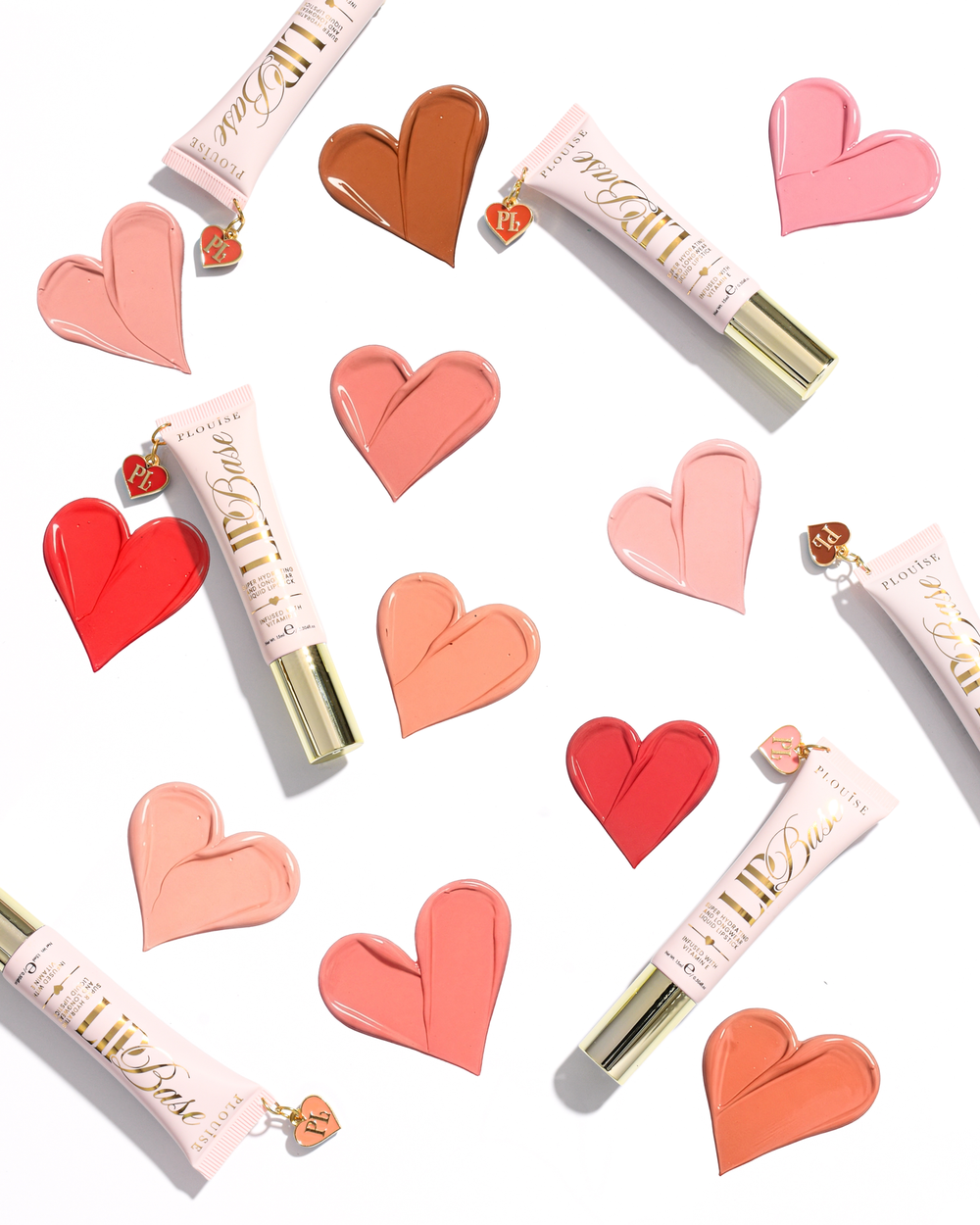 Trois tubes de base pour les lèvres P.Louise dans des tons de rose, corail et pêche, disposés sur un fond blanc avec des échantillons de lèvres en forme de cœur assortis et de petites breloques en forme de cœur.
