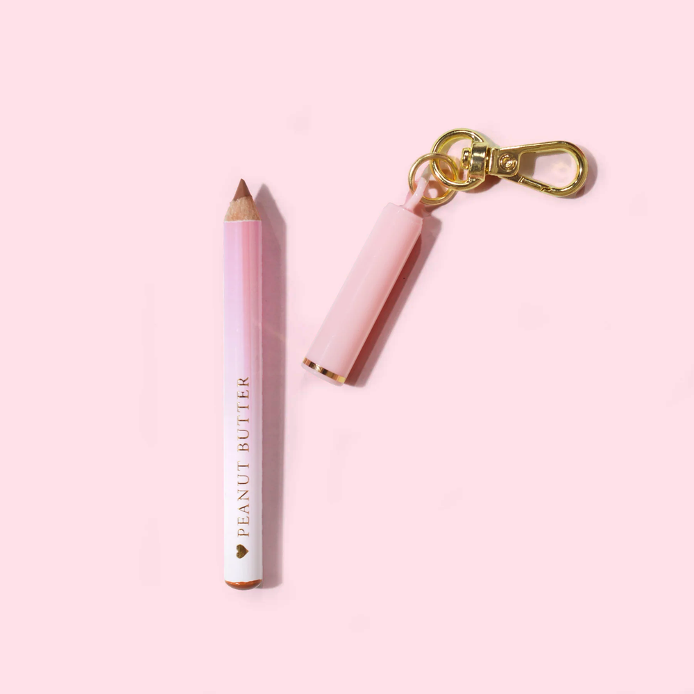 Mini delineador labial rosa P.Louise com chaveiro 'Manteiga de amendoim' em um fundo rosa claro