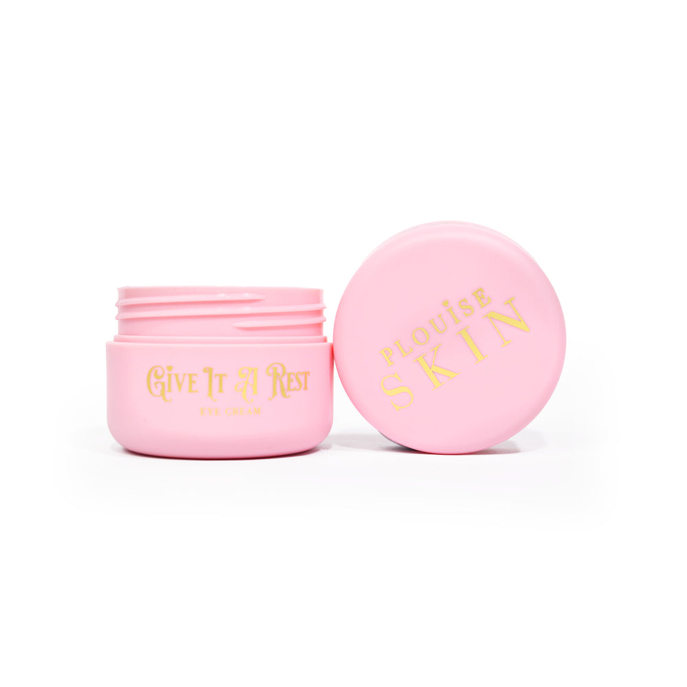 Een roze open pot P.Louise Give It A Rest Eye Cream, waarbij het deksel en de pot vanaf de zijkant zichtbaar zijn, met de merk- en productnaam op de pot in gouden letters