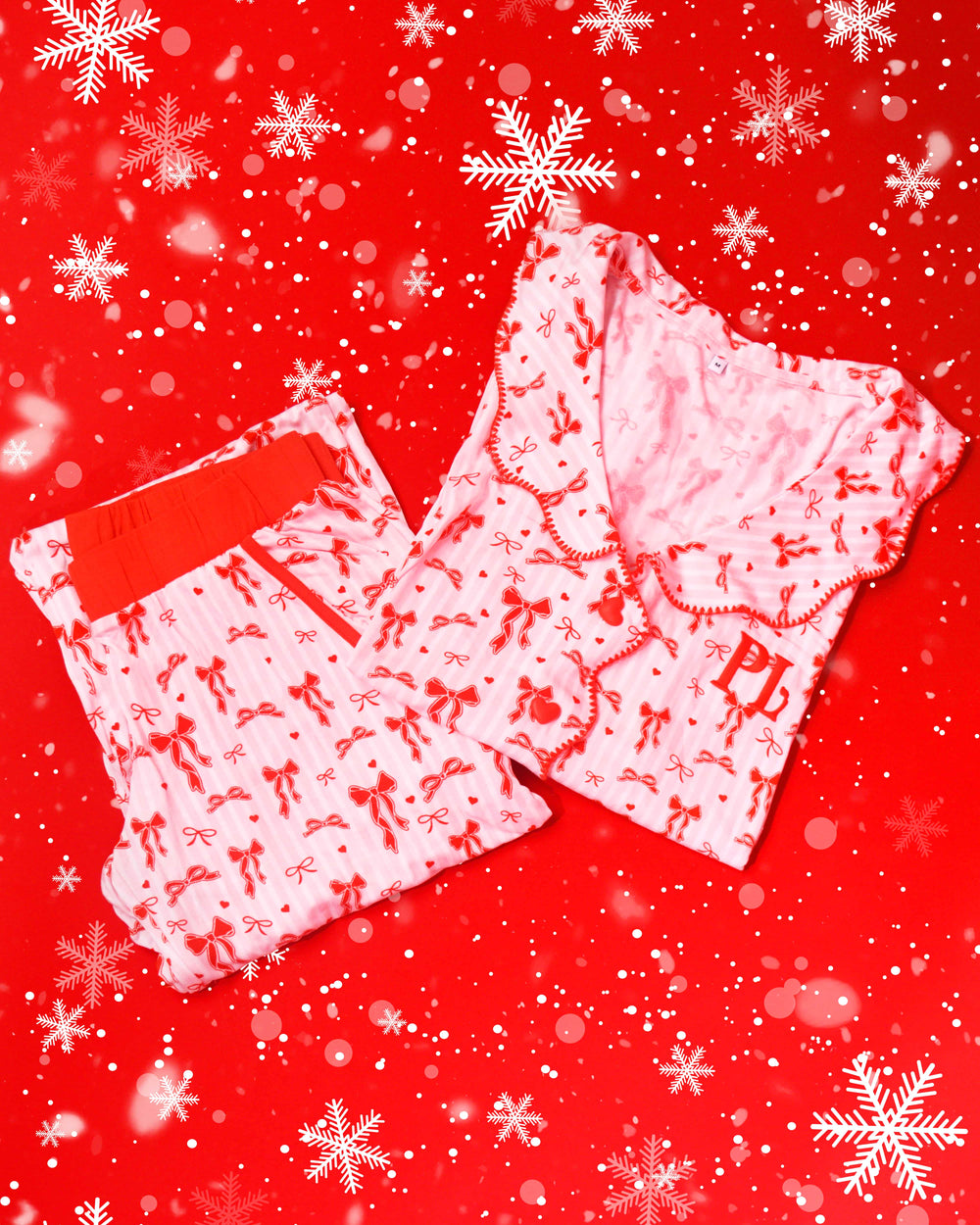 Paar roze en wit gestreepte pyjama's met rode feestelijke strikontwerpen op een rode achtergrond met sneeuwvlokken
