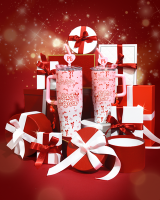 Pink P.Louise Christmas Tumbler Cups with a festive bow design surrounded by Christmas gift boxes on a red background