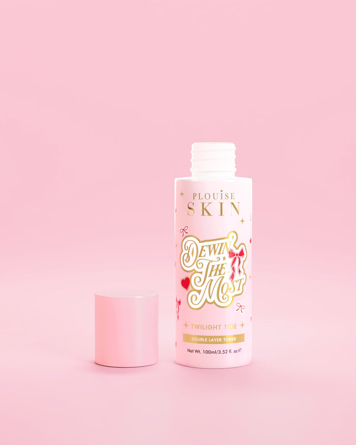 زجاجة وردية من P.Louise Dewin The MOst Double Layer Toner مع تصميمات القوس الأحمر على خلفية وردية 