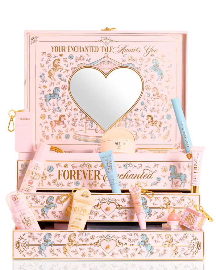 A P.Louise pastel pink, blue and yellow Christmas PR beauty gift set box labelled 'Your Enchanted Tale' with a heart-shaped mirror on the lid and open drawers, surrounded by assorted cosmetic tubes, bottles, and a small pouch on a white background.