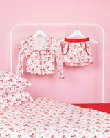 Conjunto de shorts de pijama listrados rosa e branco para meninas P.Louise Natal em cabides em um quarto rosa com roupa de cama combinando 