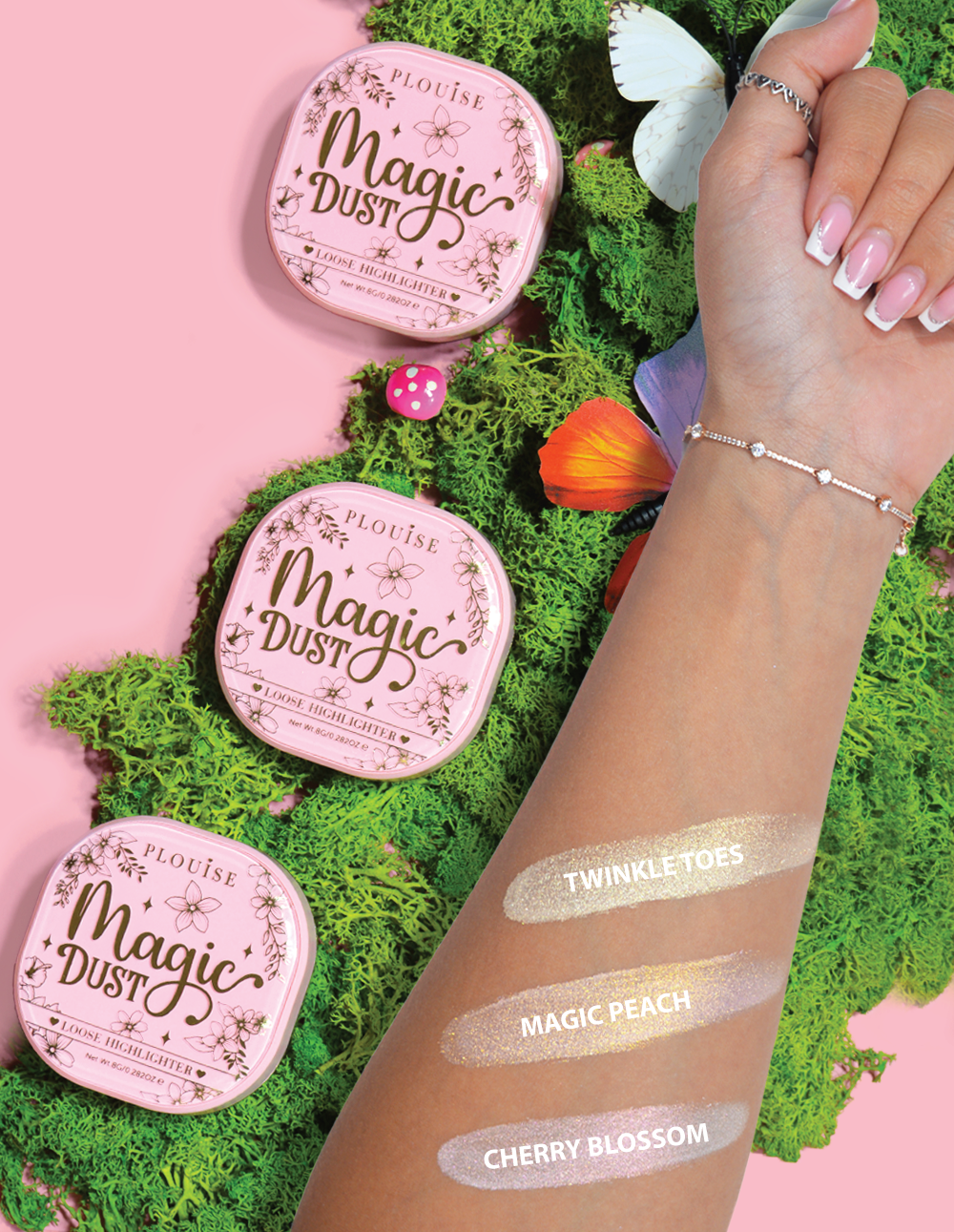 Tre kompakte løse highlightere mærket Magic Dust i nuancerne Twinkle Toes, Magic Peach og Cherry Blossom, vist på en arm med en blomstret baggrund.