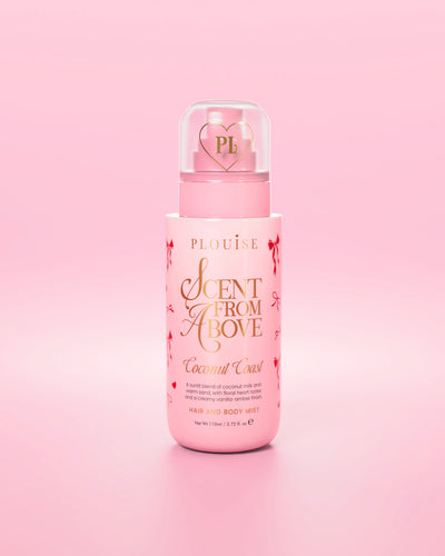 Pink bottle of 'Scent From Above' hair and body mist with red bow graphics against a pink background
