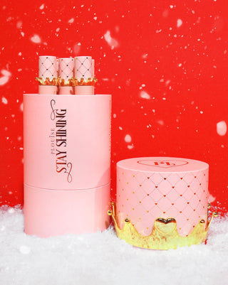 Giant Stay Shining Crown Lip Oil gift box with pink lip oils in it against a red background with snow