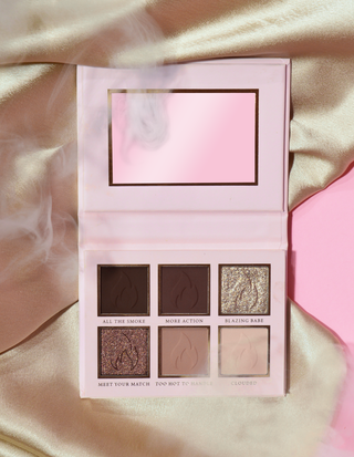 A P.Louise mini eyeshadow palette with four creamy matte shades and two shimmer eyeshadows, presented on a soft, textured surface in pink packaging