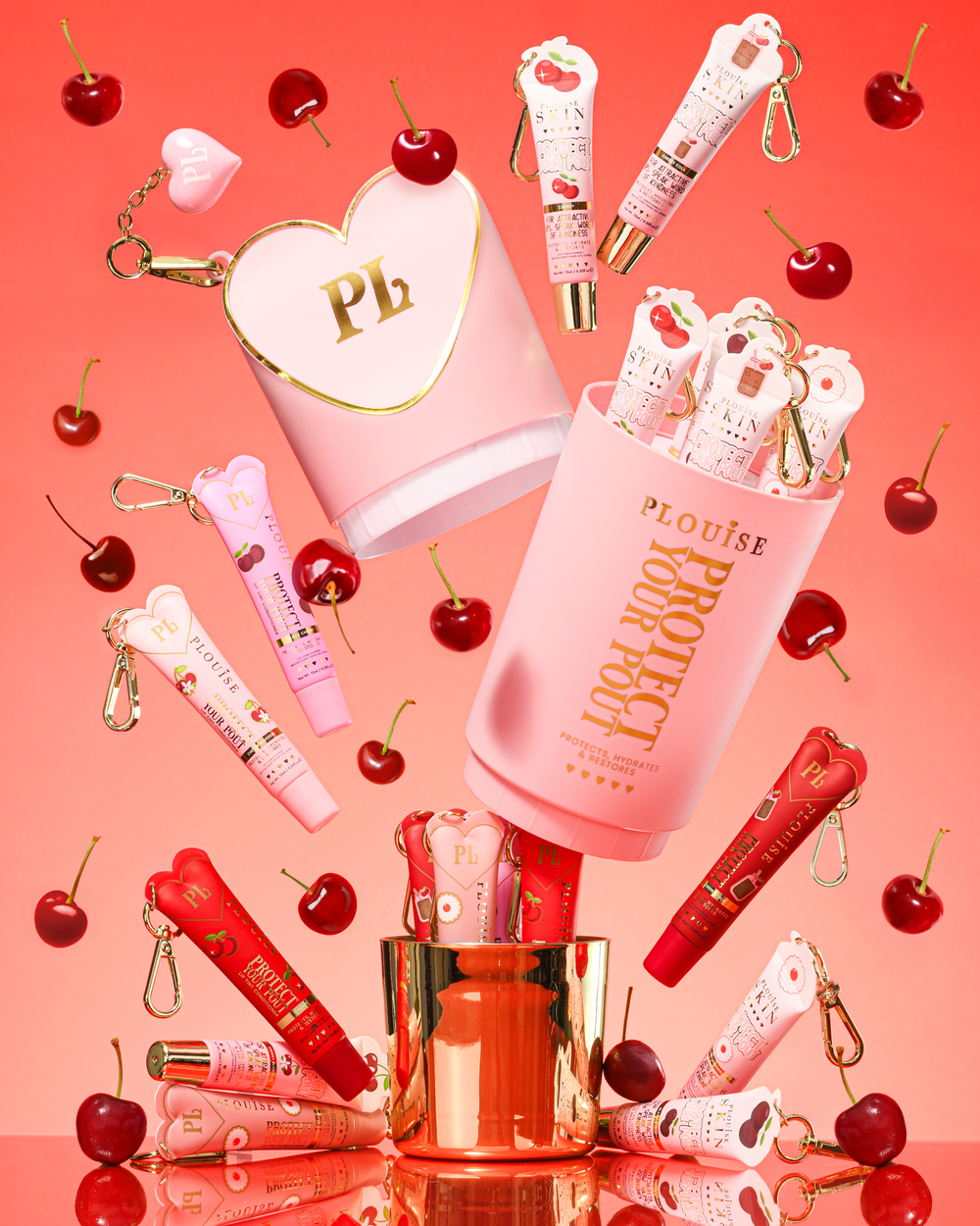 Pink XL Protect Your Pout Gavesæt, der er åbnet omgivet af kirsebær og pink og rød læbebalsam på en pink baggrund