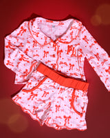 Conjunto de pijamas de Natal infantis listrados rosa e brancos com desenhos de laço vermelho sobre um fundo vermelho