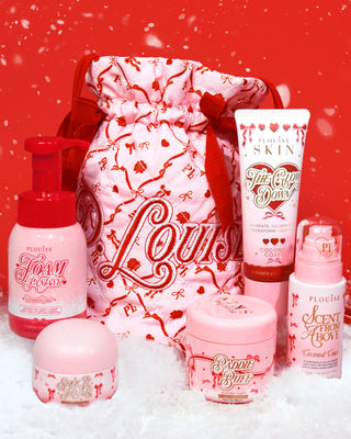 Pink Christmas P.Louise bag with red bows and a festive design surrounded by bodycare products on a red background with snow