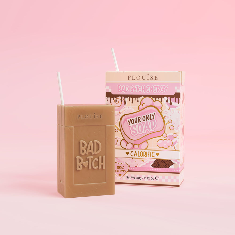 Et brunt såpestykke med 'Bad Bitch' gravert på, ledsaget av en fargerik juicebokspakke med 'Calorific' merket på den, presentert på en rosa bakgrunn.
