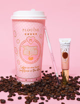 Uma imagem de produto apresentando um lápis de sobrancelha de ponta dupla ao lado de um tubo de gel para sobrancelhas, exibido em uma superfície rosa com grãos de café espalhados. O fundo tem uma xícara de café rosa com elementos de marca.