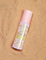 Een fles P.Louise Fix Up Mattifying Setting Spray met een roze dop en decoratieve patronen op het etiket, weergegeven op een zanderig oppervlak.