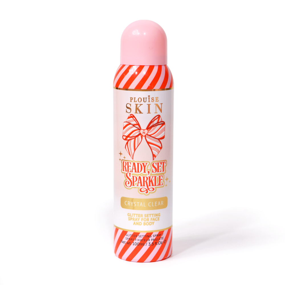 Une bouteille de P. Louise Ready Set Sparkle Christmas Glitter Setting Spray avec des rayures rouges et roses sur la bouteille et un nœud rayé rouge et rose sur fond blanc