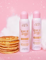 Dwie puszki aerozolowe P. Louise Ready Set Sparkle Glitter Setting Spray ze stosem naleśników i różowym tłem z błyskotkami